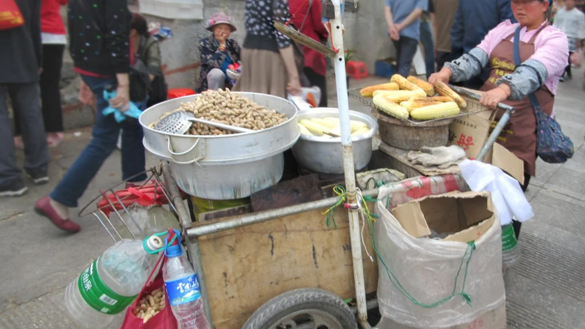 A vendor preparing corn and peanuts at a Dali street market