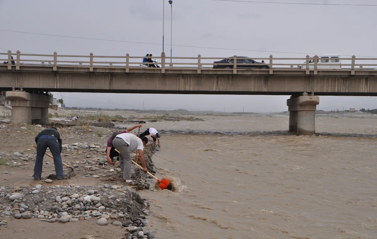 People beside a river crossing in Hotan Prefecture