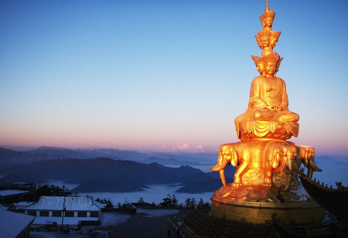 Golden statue at Mount Emei above a sea of clouds at sunrise
