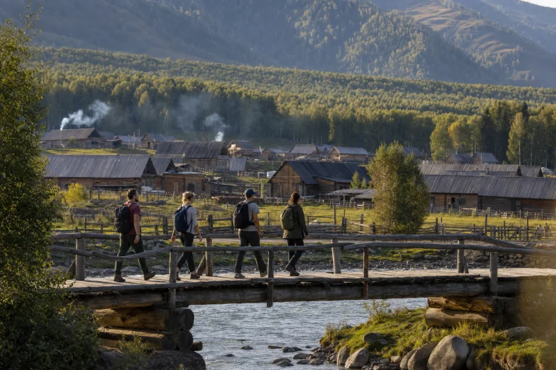 Travelers crossing a wooden bridge in Hemu Village