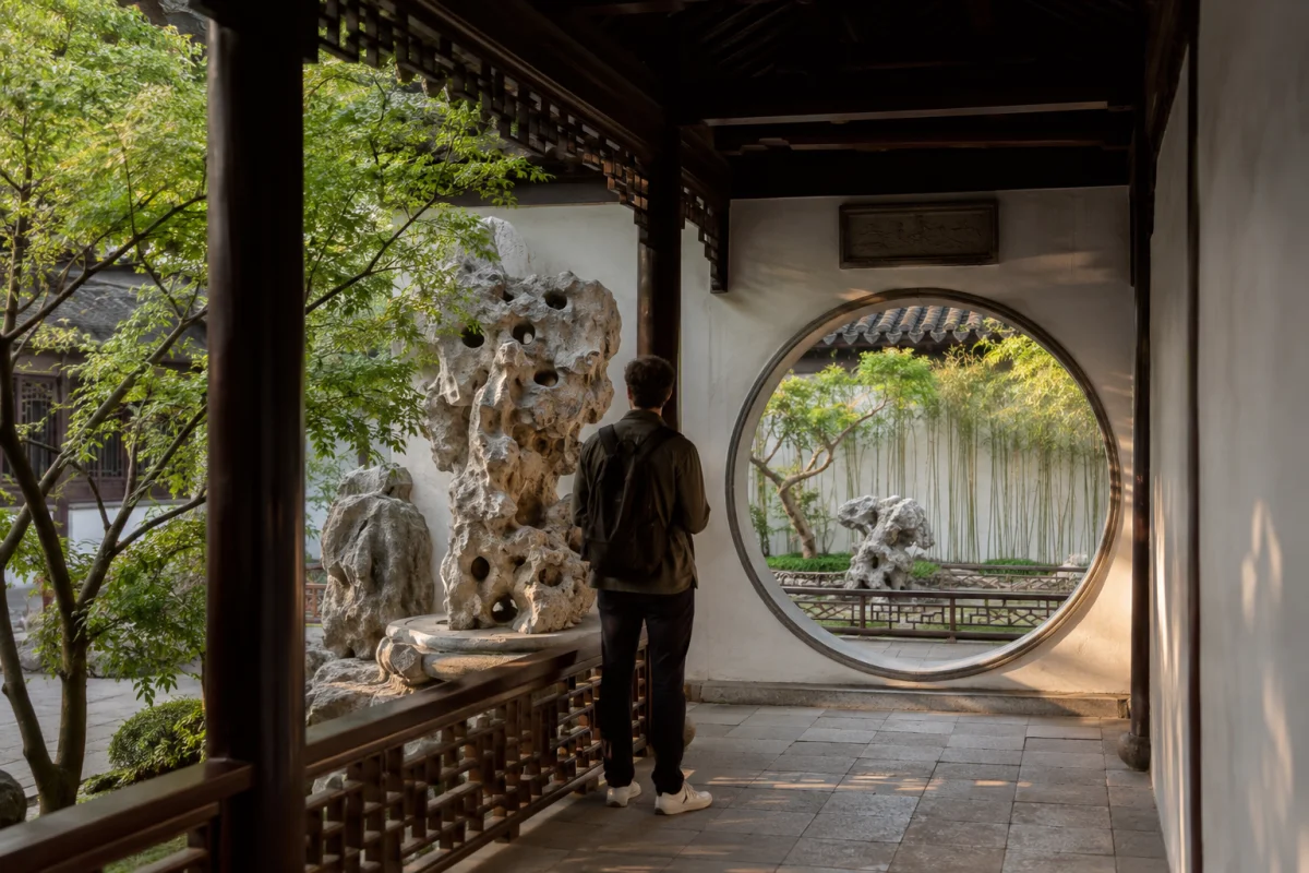 Traveler viewing Taihu stone and a moon gate in a Suzhou classical garden